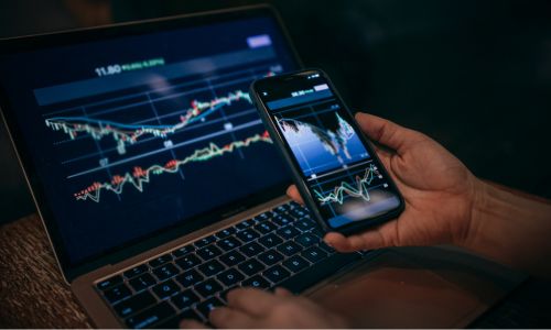This image shows a professional using both a phone and laptop — a clean, modern visual that conveys the digital/technology angle of bank–fintech partnerships without being overly literal.