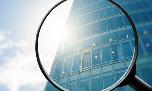 Concept art image of a magnifying inspecting the facade of a corporate building 
