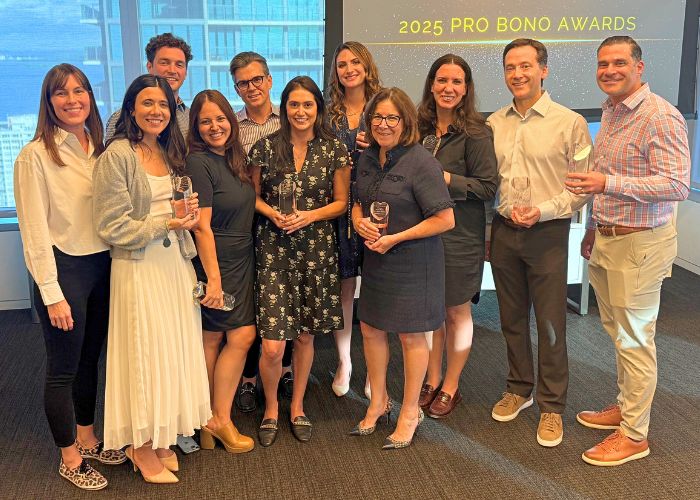 Photo 11 people mostly Bilzin Sumberg attorneys holding their Pro Bono award trophies from the 2025 Matter of the Heart Pro Bono Awards event held in October 2025.